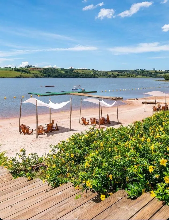 Praia com tendas, deck e flores na beira da represa